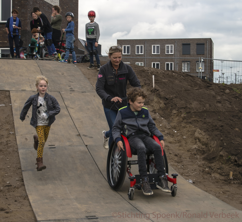 Jongen in rolstoel test onder begeleiding de hellingbaan uit
