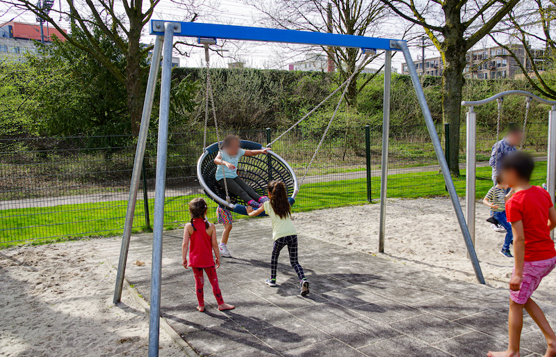 Kinderen spelen in en rondom de restschommel in Speeltuin Philipsdorp
