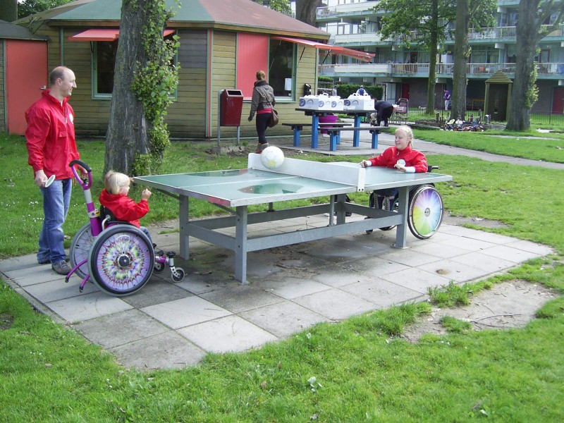 Twee kinderen in een rolstoel pingpongen met een grote bal