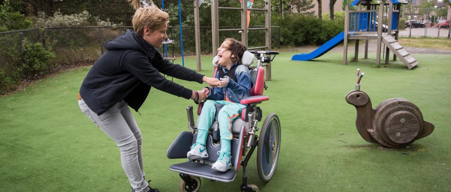 Elin in haar rolstoel speelt met een vriendje in de speeltuin