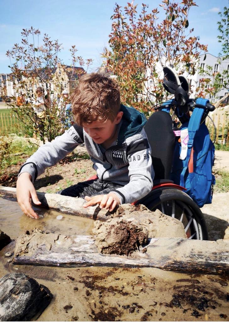 Jongen in rolstoel speelt bij de zandtafel in natuurspeeltuin Ettegerpark