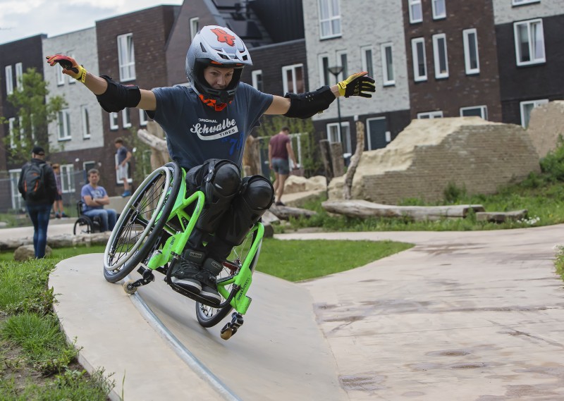 Rolstoeler met helm en knie- en elleboogbeschermers test de skatebaan in natuurspeeltuin Ettegerpark