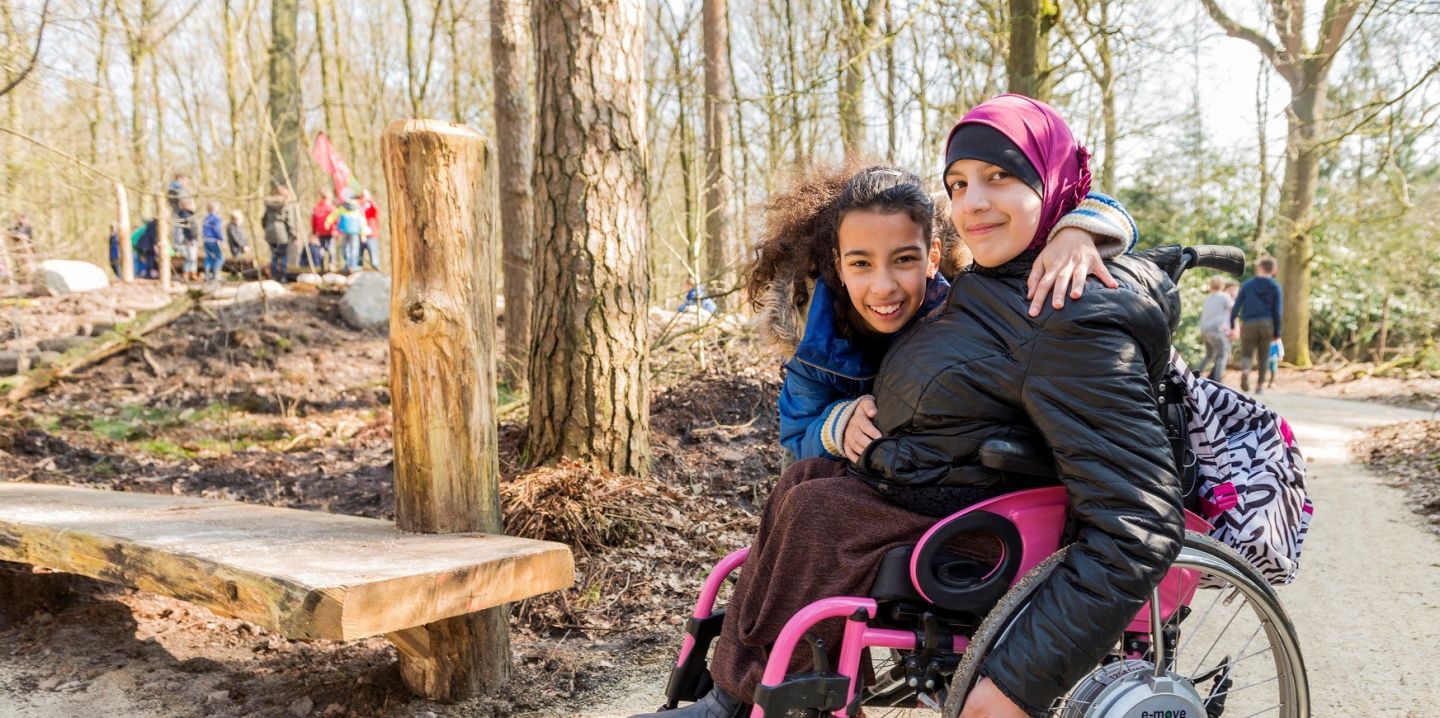 Twee meisjes, één in rolstoel, poseren samen