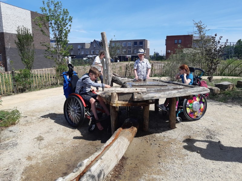 Jongens in rolstoelen spelen samen aan de zandtafel in natuurspeeltuin Ettegerpark
